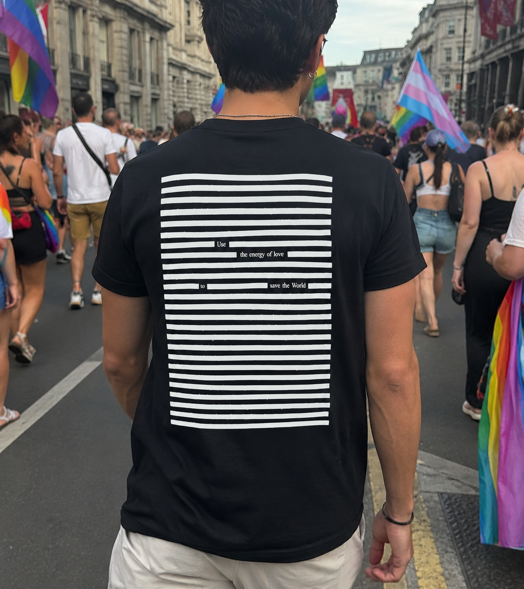 Person wearing white on black t-shirt with poetry print, walking down a pride parade